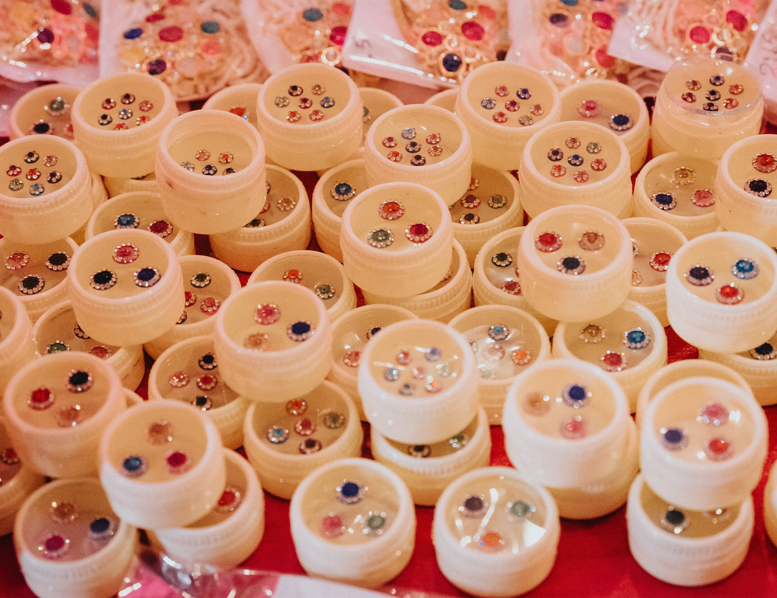 A collection of colorful bindis in small containers, showcasing a variety of decorative designs and styles.